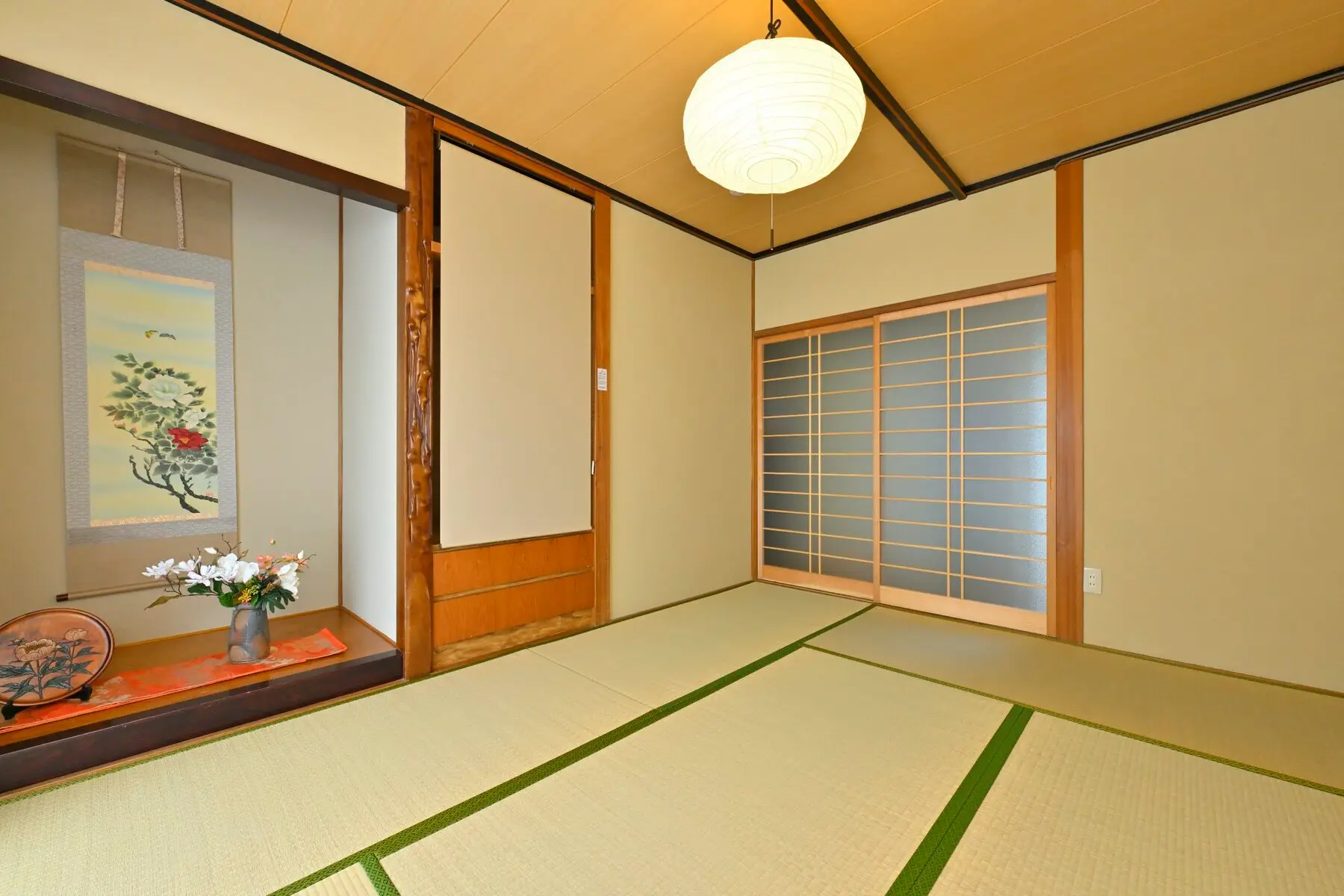 和室（一） — 生成りの壁。掛け軸と、白い提灯の照明。